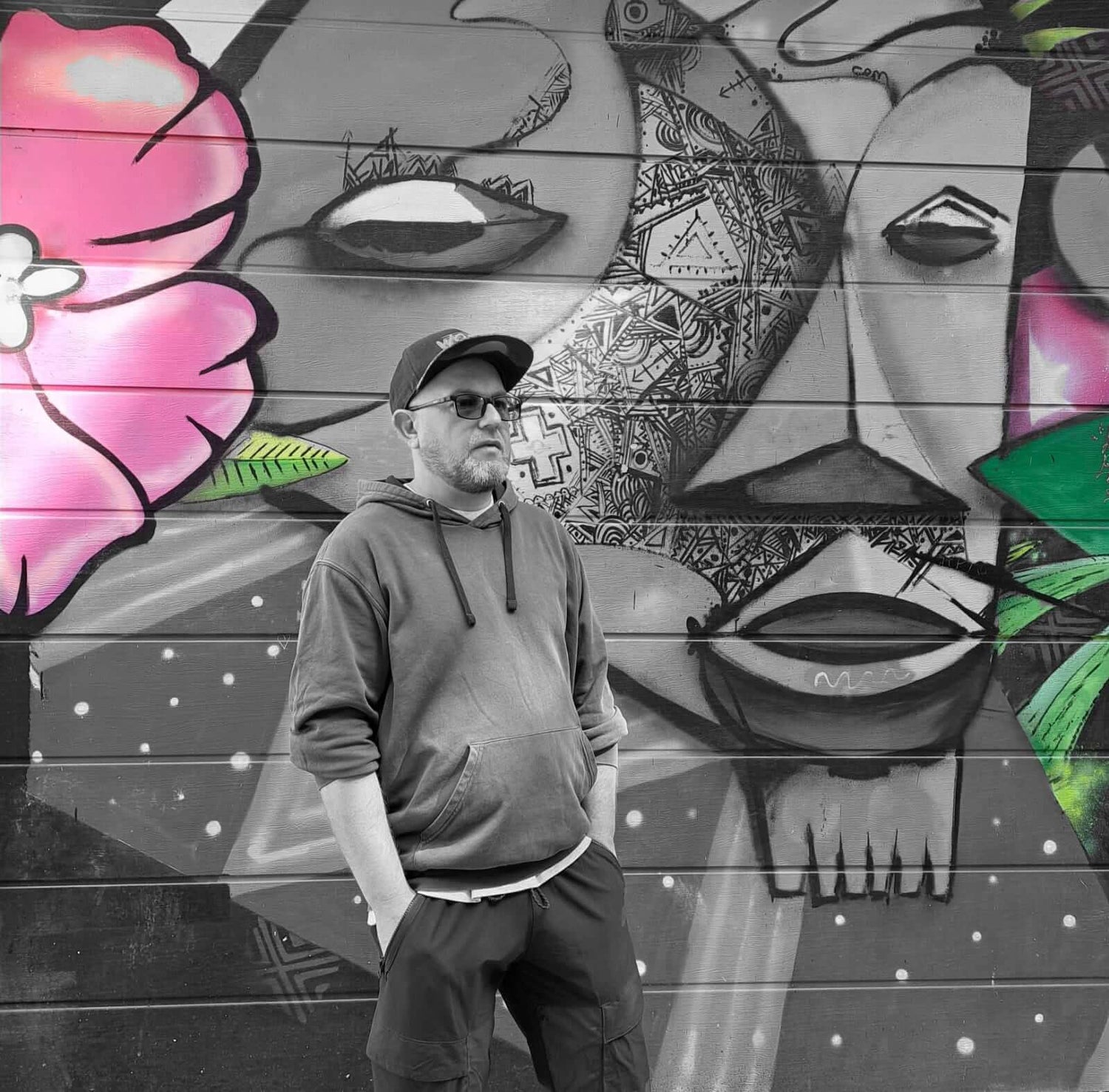 L'artiste devant une fresque colorée, représentant le fondateur de Chollala avec des motifs artistiques.